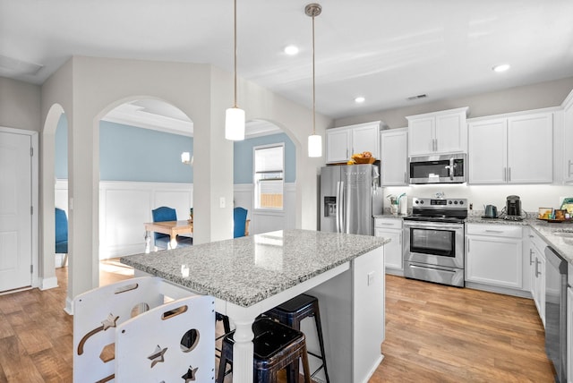 kitchen with hanging light fixtures, white cabinets, and stainless steel appliances