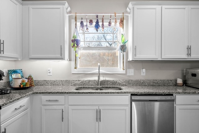 kitchen featuring stainless steel dishwasher, sink, light stone countertops, and white cabinets