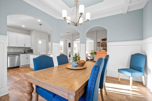 dining room featuring an inviting chandelier, light hardwood / wood-style flooring, ornamental molding, and beam ceiling