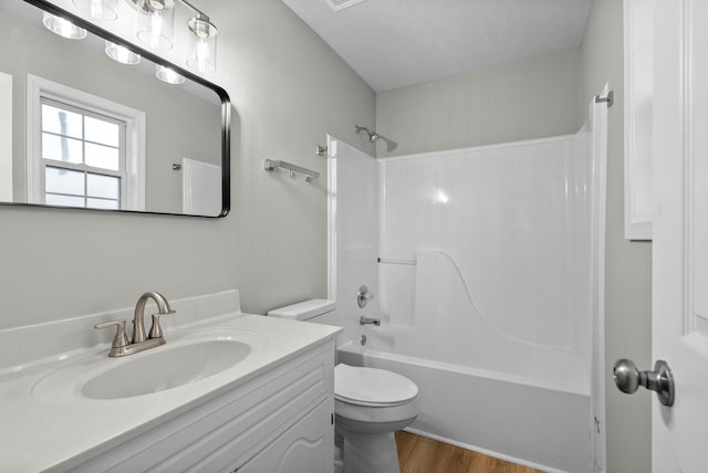 full bathroom with shower / tub combination, toilet, a textured ceiling, vanity, and hardwood / wood-style floors