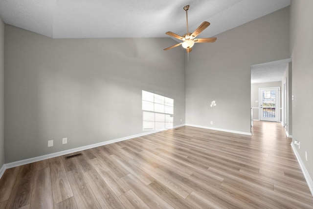 spare room with light hardwood / wood-style floors, high vaulted ceiling, ceiling fan, and a textured ceiling