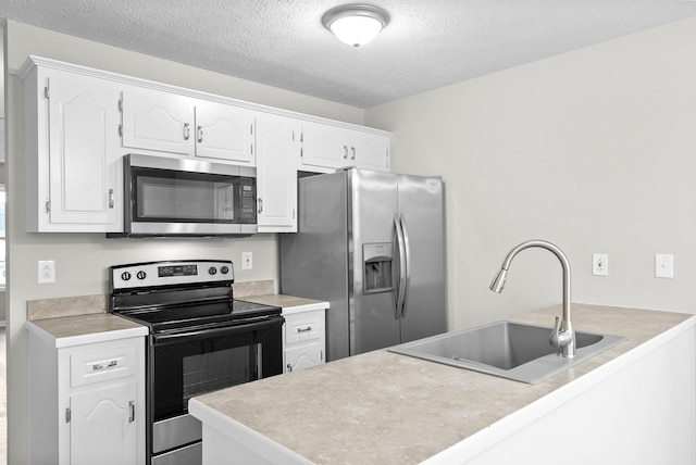 kitchen featuring sink, a textured ceiling, stainless steel appliances, kitchen peninsula, and white cabinets