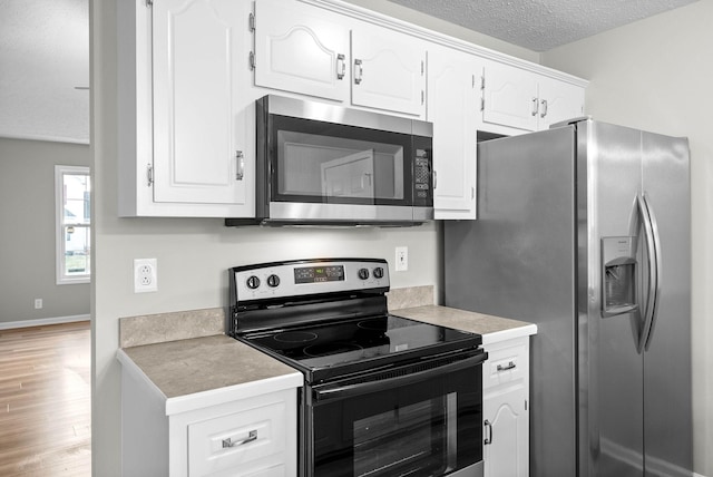 kitchen with white cabinetry, appliances with stainless steel finishes, a textured ceiling, and light hardwood / wood-style flooring