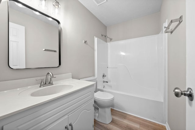 full bathroom featuring tub / shower combination, toilet, a textured ceiling, vanity, and hardwood / wood-style floors