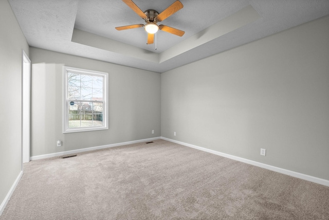 carpeted spare room featuring ceiling fan, a tray ceiling, and a textured ceiling