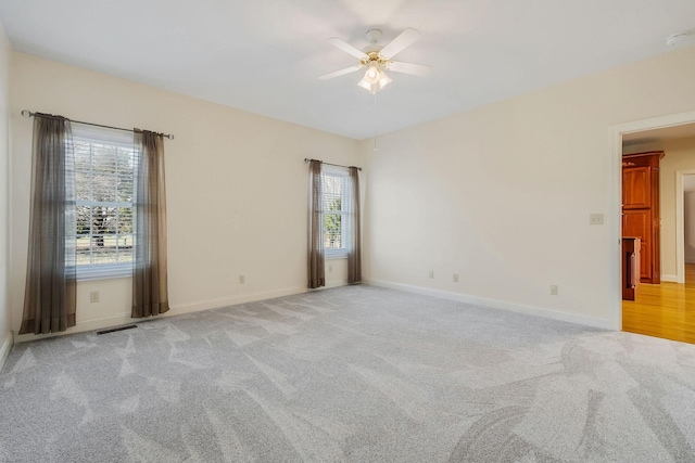 empty room featuring ceiling fan and light colored carpet