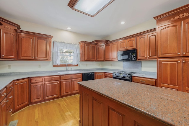 kitchen featuring light hardwood / wood-style floors, sink, black appliances, and light stone countertops