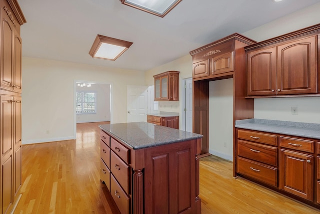 kitchen with light hardwood / wood-style flooring, dark stone counters, and a kitchen island