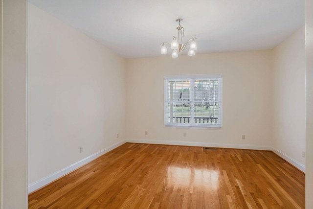 unfurnished room featuring an inviting chandelier and light hardwood / wood-style floors