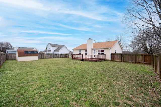 view of yard with a storage shed, a wooden deck, a fenced backyard, and an outbuilding