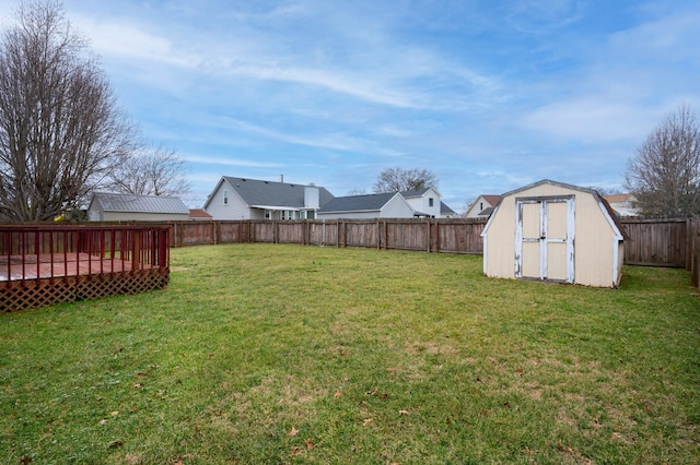 view of yard with a shed, a deck, a fenced backyard, and an outdoor structure