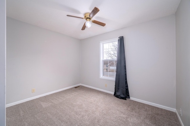 empty room with carpet floors, visible vents, baseboards, and a ceiling fan