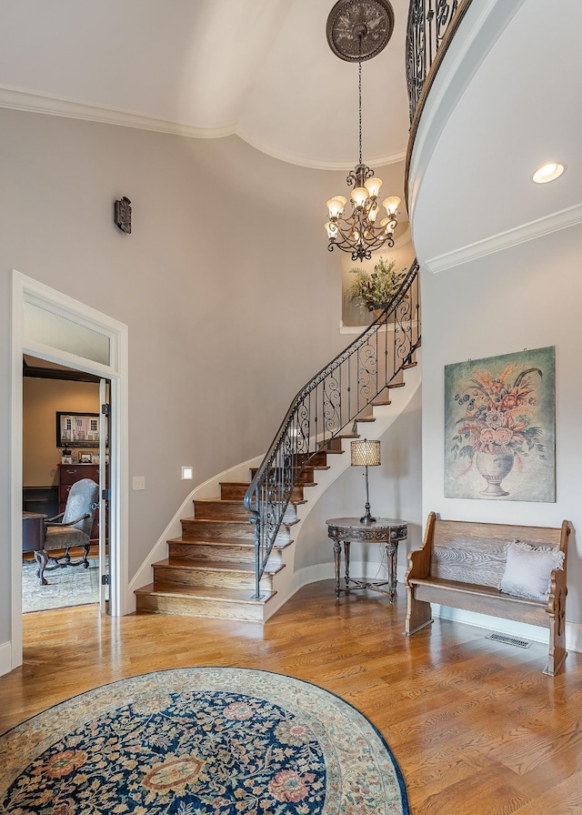 foyer with hardwood / wood-style floors, crown molding, and a high ceiling