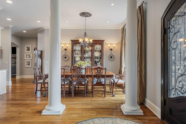 entrance foyer featuring ornamental molding, an inviting chandelier, ornate columns, and hardwood / wood-style floors