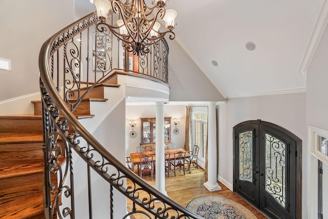 foyer entrance with french doors, decorative columns, high vaulted ceiling, hardwood / wood-style flooring, and ornamental molding