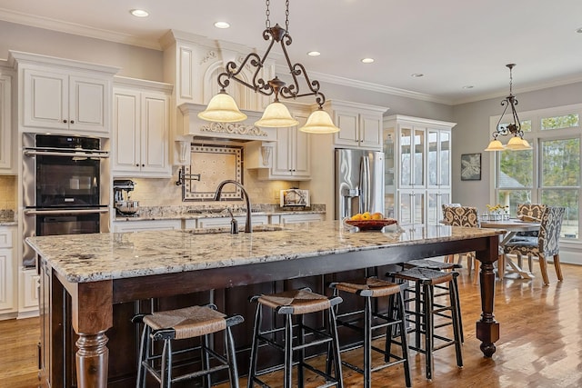 kitchen featuring hanging light fixtures, a large island, stainless steel appliances, light stone counters, and sink