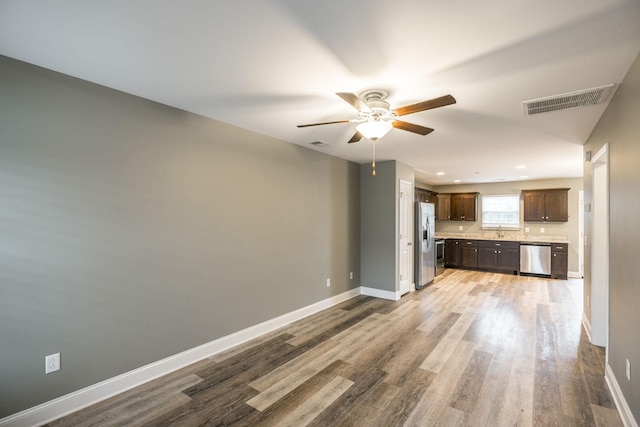 kitchen with stainless steel appliances, dark brown cabinetry, light hardwood / wood-style floors, sink, and ceiling fan