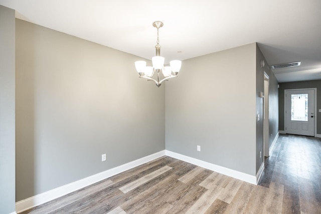 empty room featuring hardwood / wood-style flooring and a notable chandelier