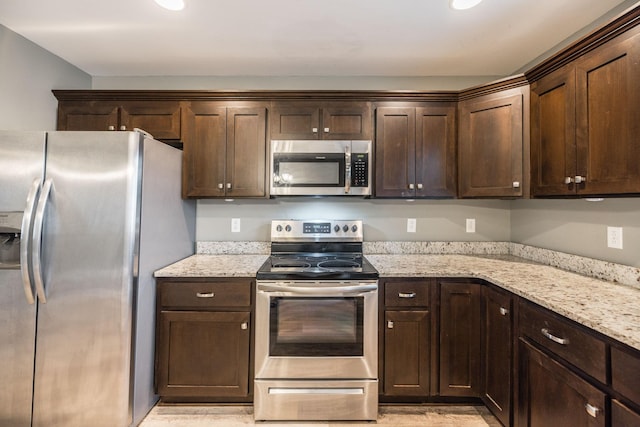 kitchen featuring light wood-type flooring, light stone countertops, stainless steel appliances, and dark brown cabinetry