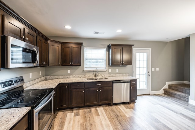 kitchen featuring light hardwood / wood-style flooring, sink, dark brown cabinets, light stone counters, and appliances with stainless steel finishes