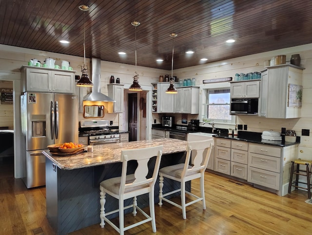 kitchen with exhaust hood, pendant lighting, stainless steel appliances, and a kitchen island