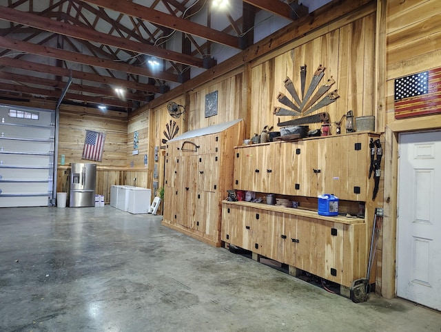 garage with stainless steel refrigerator with ice dispenser and wood walls