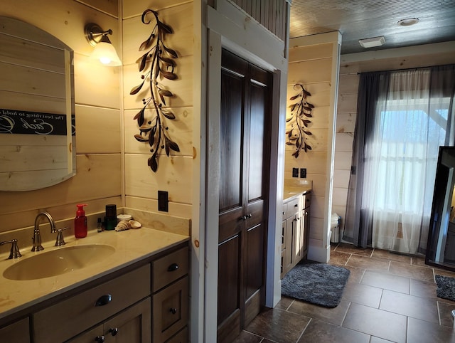 bathroom with a wealth of natural light, wooden walls, and vanity