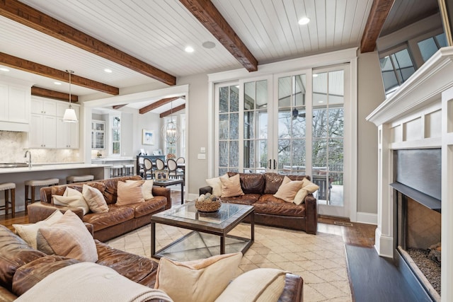 living room featuring light wood finished floors, a fireplace, a wealth of natural light, and beamed ceiling