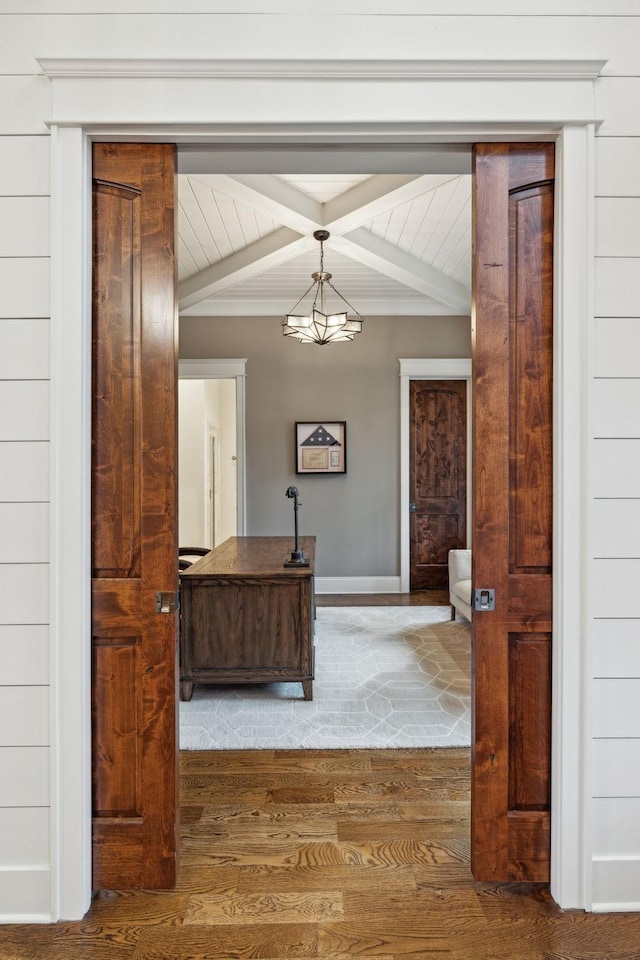 corridor with an inviting chandelier, wood finished floors, beam ceiling, and baseboards