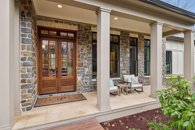 entrance to property featuring stone siding, french doors, and covered porch