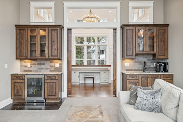 bar featuring wine cooler, a notable chandelier, a sink, and backsplash