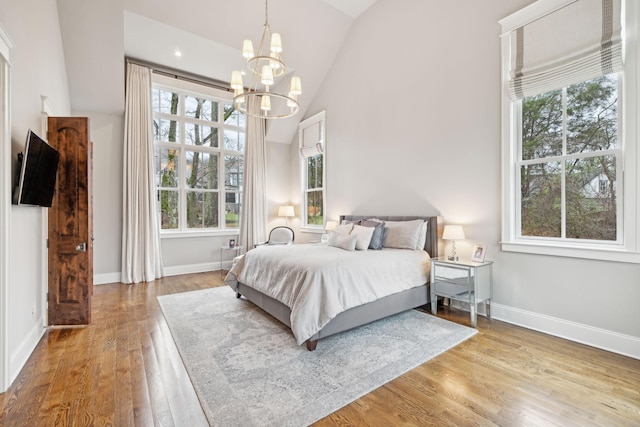 bedroom featuring high vaulted ceiling, light wood-style flooring, baseboards, and an inviting chandelier