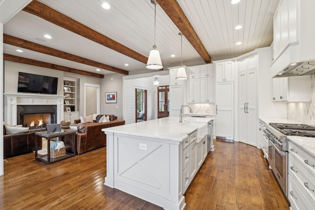 kitchen featuring a kitchen island with sink, white cabinetry, range with two ovens, and open floor plan