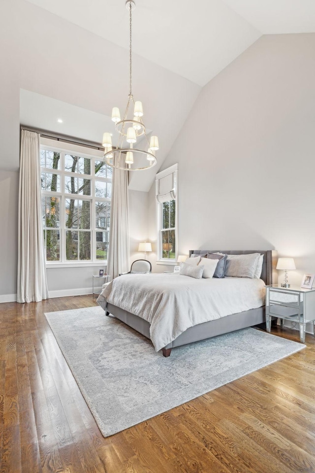 bedroom with multiple windows, vaulted ceiling, and wood finished floors