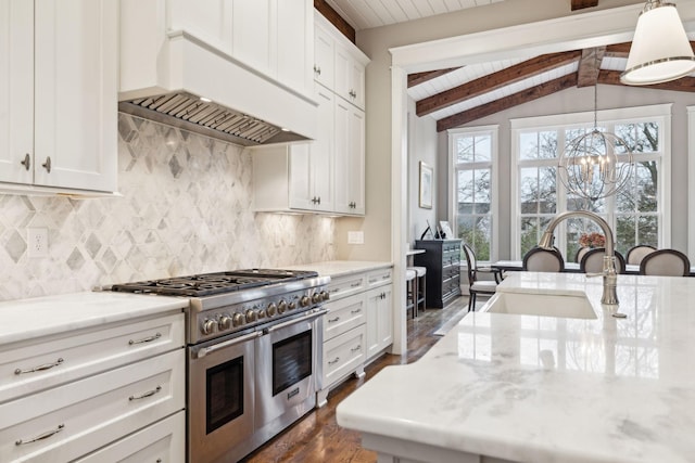 kitchen featuring double oven range, decorative light fixtures, custom exhaust hood, and white cabinetry