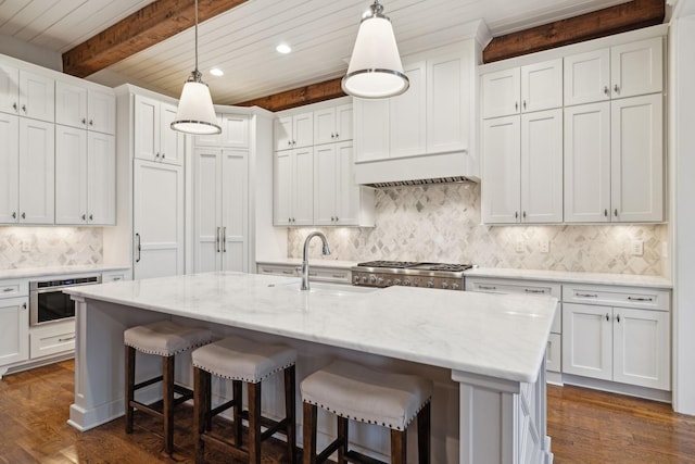 kitchen featuring stove, white cabinets, a kitchen island with sink, stainless steel oven, and light stone countertops