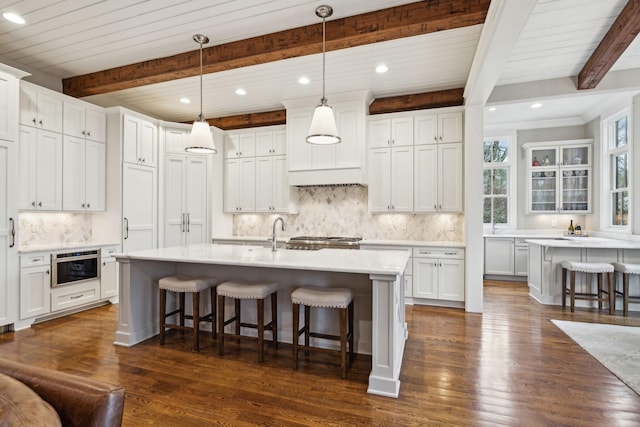 kitchen with white cabinets, a kitchen island with sink, light countertops, and a kitchen breakfast bar