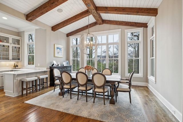 dining room with a chandelier, a healthy amount of sunlight, vaulted ceiling with beams, and baseboards