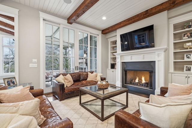 living area featuring built in shelves, beam ceiling, wood ceiling, light wood-type flooring, and a lit fireplace