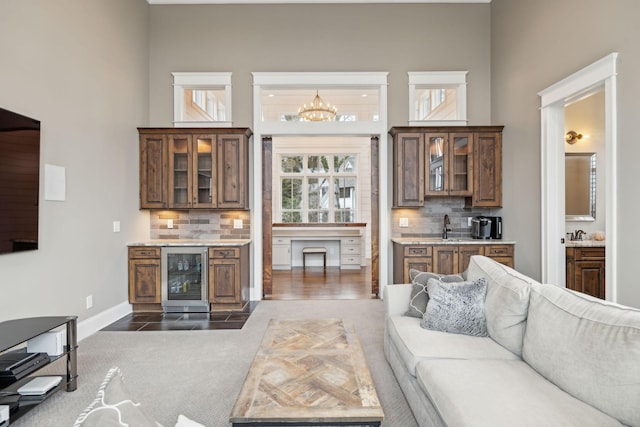 living room with a chandelier, wine cooler, a high ceiling, and baseboards