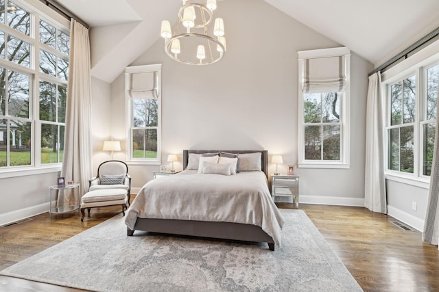 bedroom with baseboards, visible vents, vaulted ceiling, and wood finished floors