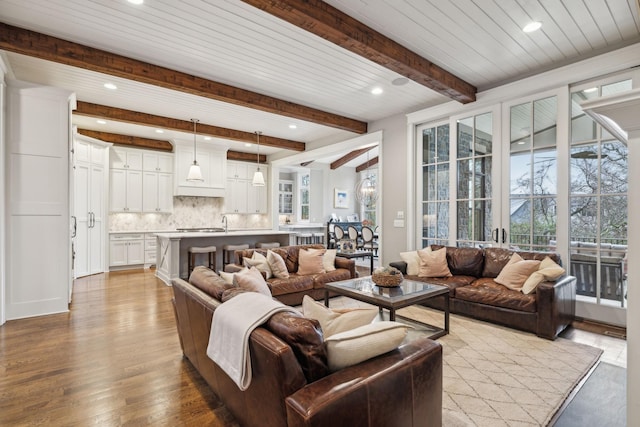 living room featuring light wood-type flooring, plenty of natural light, beam ceiling, and recessed lighting