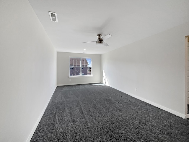 empty room with visible vents, dark carpet, and baseboards