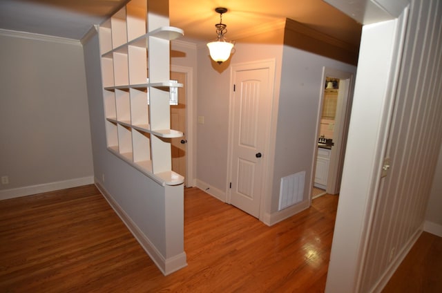 hall with ornamental molding and hardwood / wood-style floors