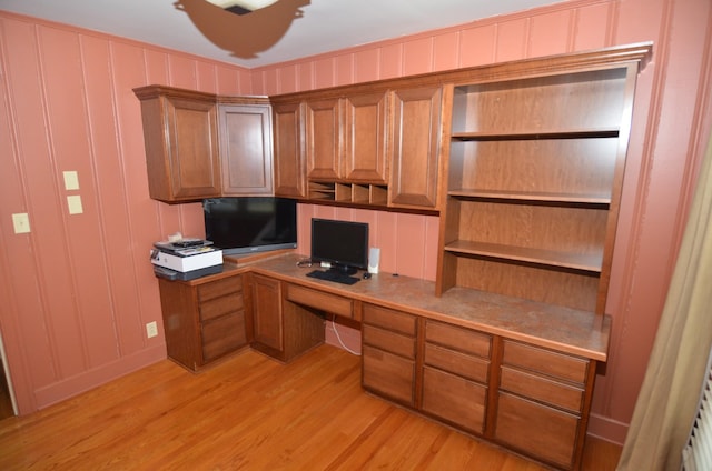 unfurnished office featuring light hardwood / wood-style flooring and built in desk