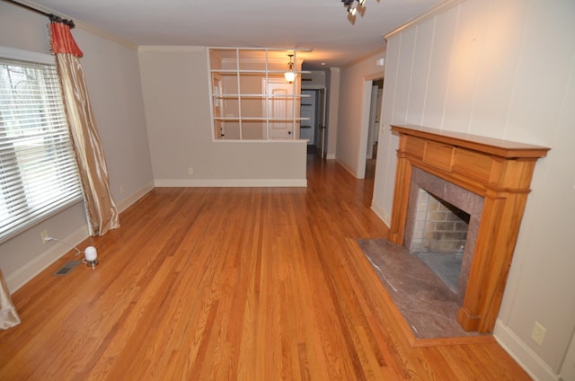 unfurnished living room featuring light hardwood / wood-style flooring, crown molding, and a fireplace