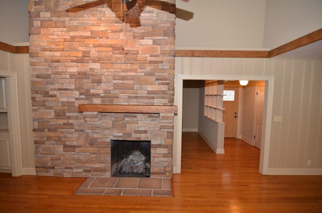 unfurnished living room with a fireplace, a towering ceiling, and light hardwood / wood-style floors