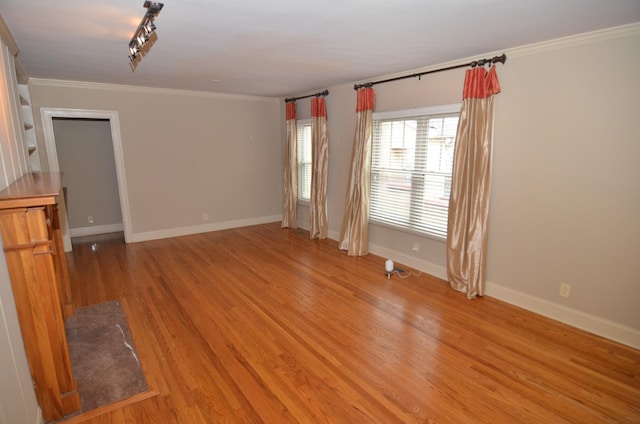 spare room with rail lighting, ornamental molding, and light wood-type flooring