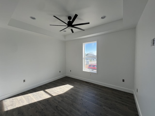 spare room with ceiling fan, a raised ceiling, and dark hardwood / wood-style floors