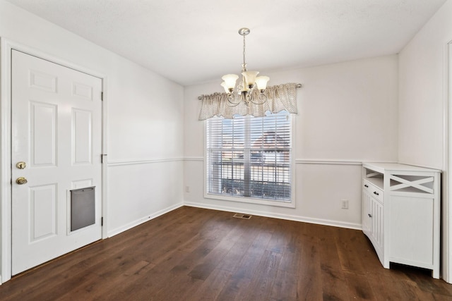 unfurnished dining area featuring dark wood-style floors, baseboards, visible vents, and an inviting chandelier